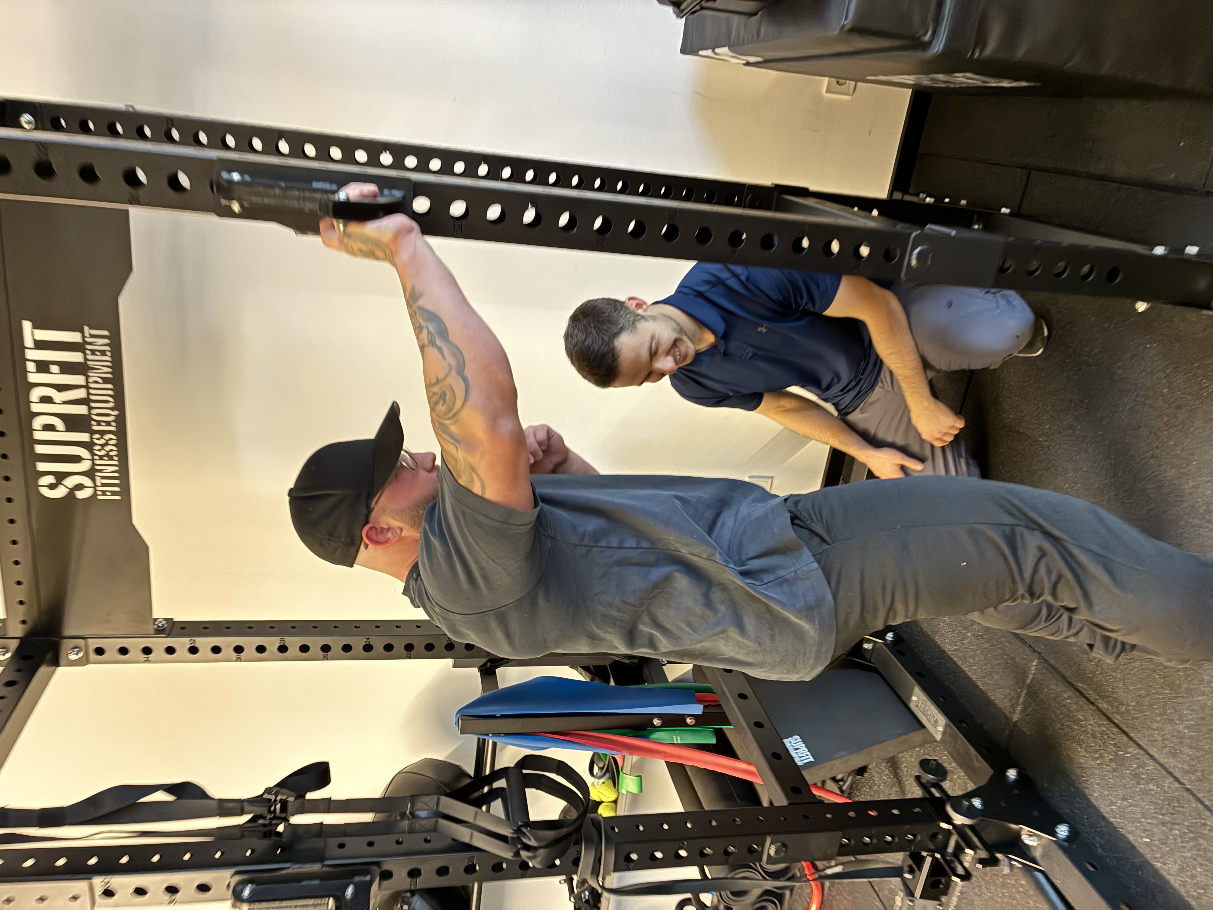 Mentorship-Teilnehmer arbeitet im Squat-Rack unter Supervision – Kraft- und Rehabilitationstraining am echten Fall.